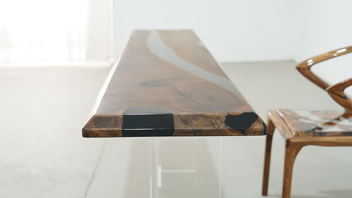 A long straight-edge dining or coffee table made of wood with black resin inlays, accompanied by a uniquely designed wooden chair with resin details