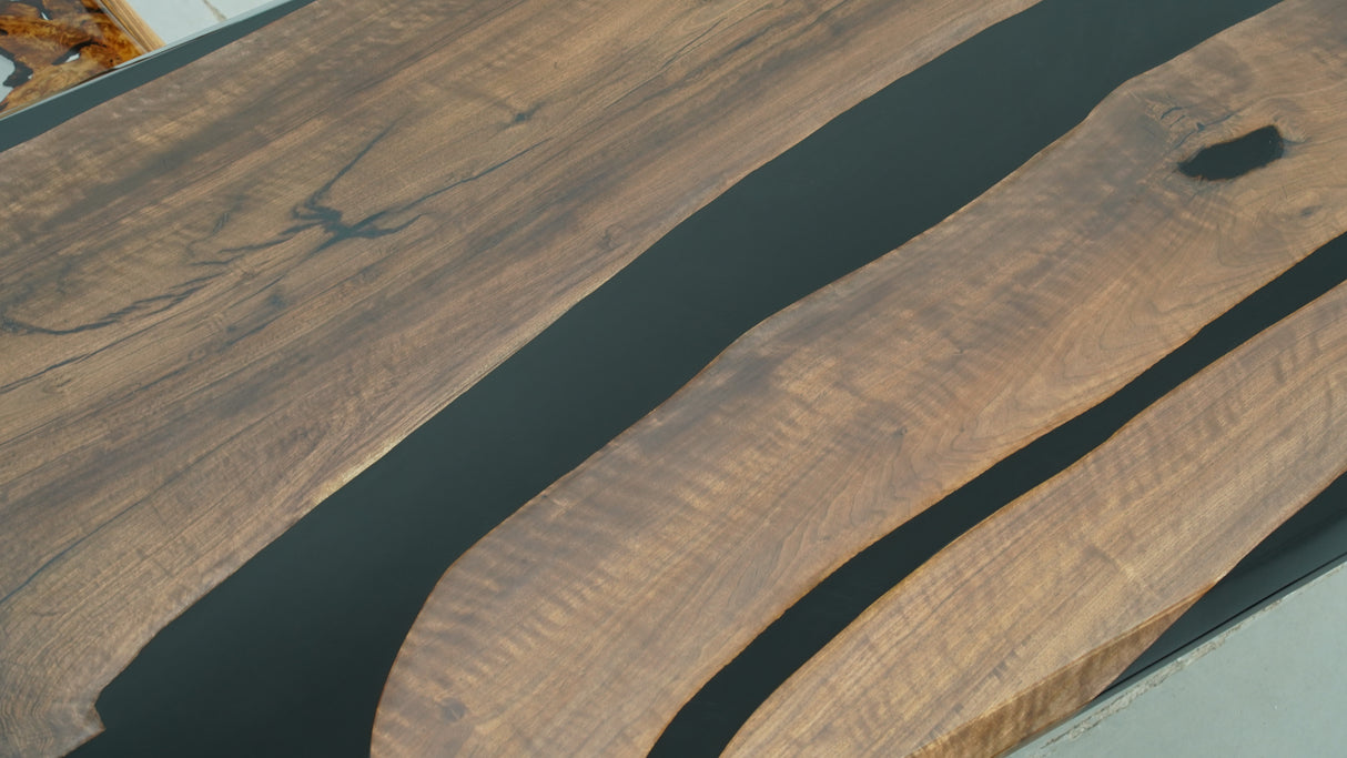 A dining table made of walnut wood with dark black resin inlays