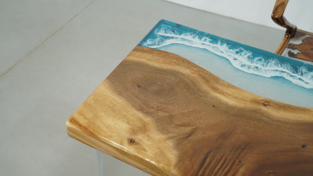 A stunning straight-edge resin table with a natural wood grain pattern merging into a blue resin section resembling ocean waves
