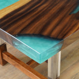 Close - up of a wooden table corner with a turquoise epoxy - resin inlay, showcasing the smooth finish and color transition.