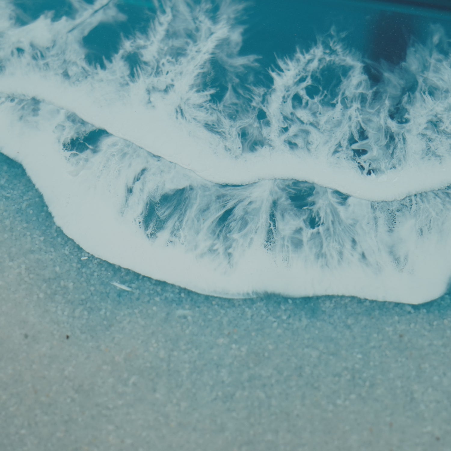 A stunning straight-edge resin table with a natural wood grain pattern merging into a blue resin section resembling ocean waves