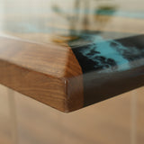 Close - up of a wooden table corner with a blue - black epoxy - resin inlay, showcasing the smooth transition between materials.