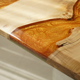 Close - up of a wooden tabletop with an inlaid section of swirling orange epoxy resin, showcasing the seamless blend of materials.