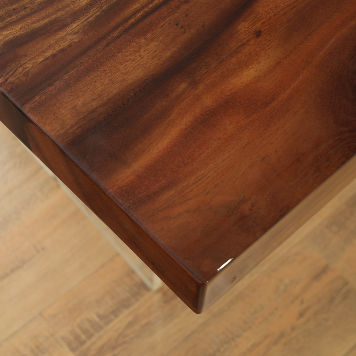 Close - up of a dark brown wooden table corner with a glossy finish.