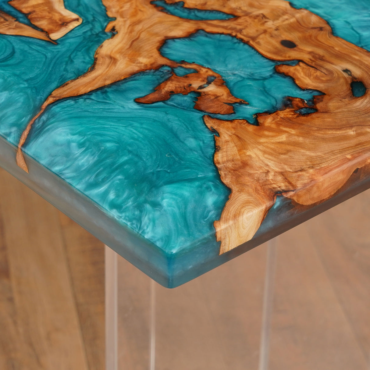 Close - up of a wooden tabletop with a vibrant teal epoxy resin inlay, showcasing the intricate blend of materials.