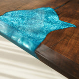 Close - up of a table corner with a blend of brown wood and blue epoxy resin, showing intricate resin patterns.