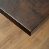 Close - up of a dark wooden tabletop corner with a smooth finish.