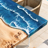 Luxury coastal dining table featuring natural poplar live edge wood, deep blue ocean resin, and elegant woven patio chairs