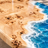 Modern beach-inspired coffee table combining golden poplar burl wood with crystal blue epoxy resin and realistic shoreline wave effects