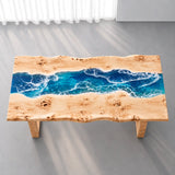 Rectangular poplar wood and blue epoxy dining table supported by a matching solid wood trestle base with a horizontal stretcher