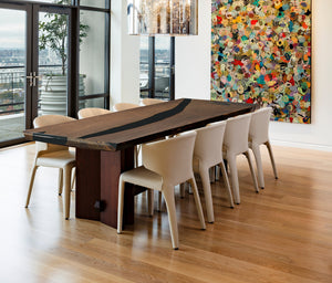 A long straight-edge dining or coffee table made of wood with black resin inlays, accompanied by a uniquely designed wooden chair with resin details